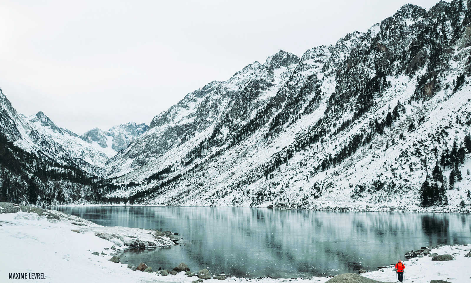 Le Lys – Cauterets in France - a person standing in the snow near a lake.