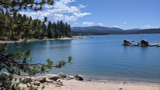 View of a peaceful lake surrounded by towering mountains at China Peak Mountain Resort, Lakeshore, California, on a clear, sunny day.