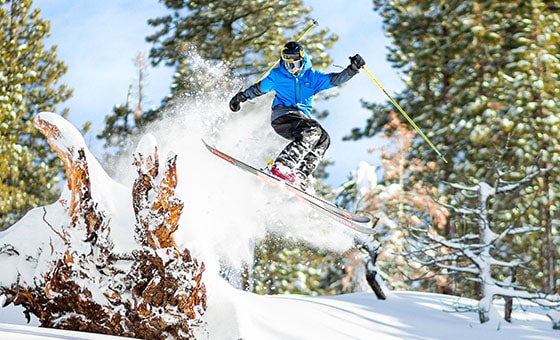 A skier and snowboarder in action at Dodge Ridge ski resort in Pinecrest, California, gliding down the snowy slopes with a group of skiers in the background.