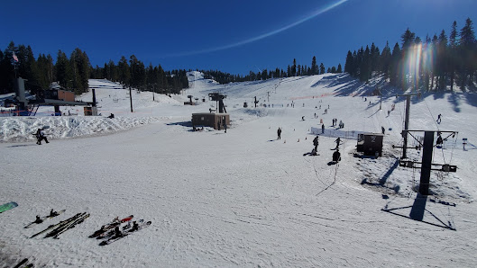 A bustling winter sports scene at Dodge Ridge ski resort in Pinecrest California complete with an operating ski lift. Snowmobiles dot the chilly landscape indicating active snow sports.
