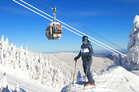 A skier glides down the slopes at Mont-Orford in Quebec, Canada. A ski lift ascends the hill in the backdrop, completing this winter sports scene highlighted by a ski resort and a charming chalet.
