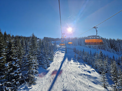 Ski lift in operation at Stuhleck ski resort in Styria, Austria, amidst a scenic winter landscape. Skiers in action and a cozy chalet complete the picturesque winter sports scene.