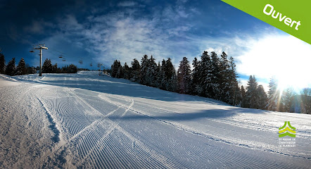 A winter sports scene at Great Divide Montana showcasing a bustling ski resort with a chalet and ski lift in the background. A skier is also visible enjoying the snowy terrain.