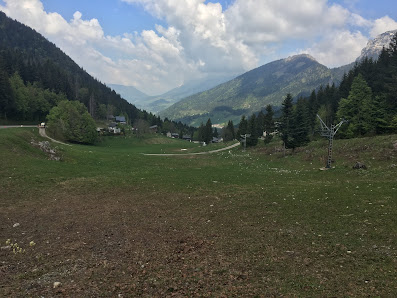A picturesque view of Station Le Planolet - Saint Pierre de Chartreuse in France featuring a lovely chalet and ski resort set amidst a mountain landscape on a sunny day with a visible ski lift.