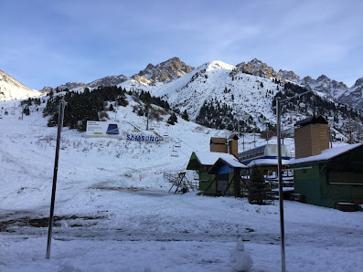 A picturesque view of the Shymbulak ski resort in Almaty Kazakhstan. Features a chalet against a majestic mountain backdrop indicating a vibrant winter sports scene.