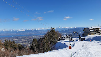 A scenic winter view at Monts Jura - Station Crozet - Lelex in France, featuring a bustling ski resort nestled amidst snow-capped mountains, with a charming chalet and a skier in action.