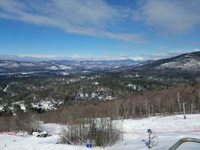 View of Cranmore Mountain Resort featuring a bustling ski resort with a ski lift and chalet, surrounded by snow-covered slopes in Conway, New Hampshire.