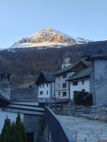 View of the majestic Piani di Bobbio mountains in Italy, with a charming challet nestled amidst the snow-covered landscape. Skiers dot the scene, enjoying the bustling ski resort.