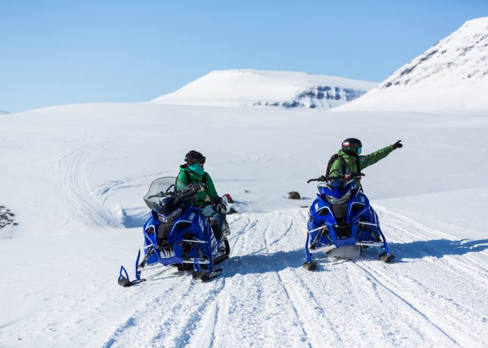 A snowmobile in the foreground on Disko Island Greenland surrounded by snowy terrain. Winter sports activities are suggested in the background.