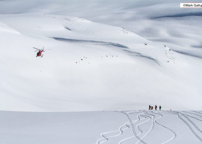 A lively winter sports scene on Disko Island Greenland. Skiers glide down the slopes of a ski resort with a ski lift seen in the backdrop. A group of skiers navigate the snowy landscape together.