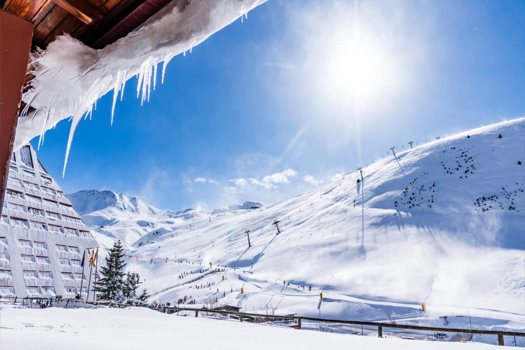A captivating winter scene at Astún ski resort in Aragon, Huesca, Spain featuring snow-covered slopes bustling with athletes and a cozy chalet nestled in the glorious snowy landscape.