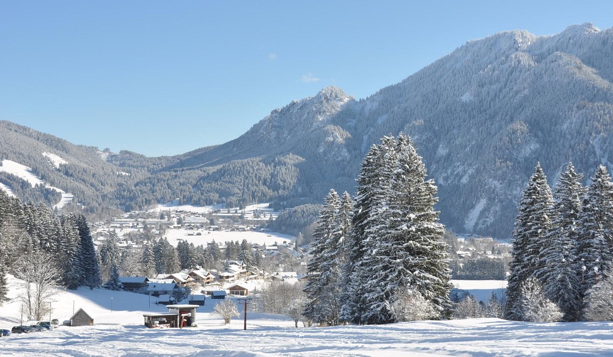 Kolbensattel – Oberammergau in Germany - a snowy landscape with trees and mountains in the background.