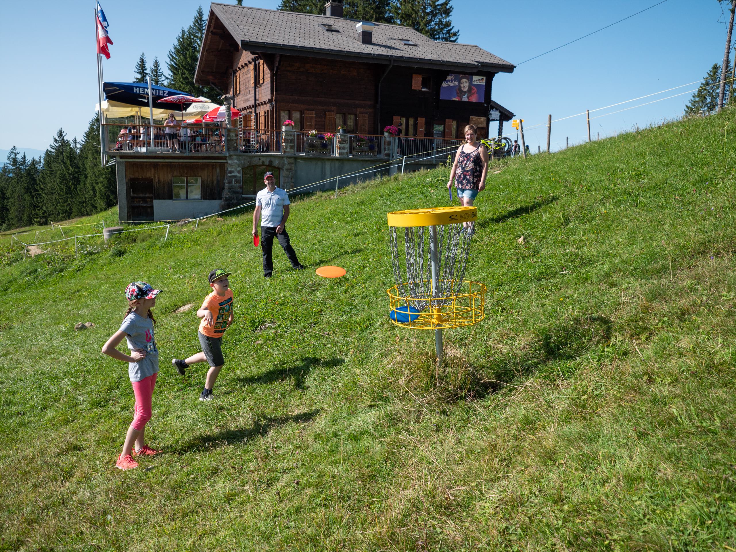 A scenic view from La Berra Switzerland capturing a ski resort surrounded by snow-covered landscape. A ski lift and challet are discernible and a winter sports scene is underway.