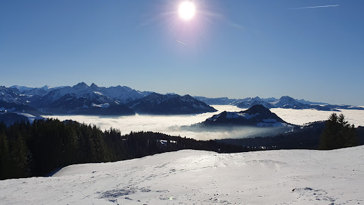 Winter scene at La Berra in Switzerland, featuring a ski resort with active winter sports, a cozy challet, surrounded by serene snow-covered mountains and winter scenery.