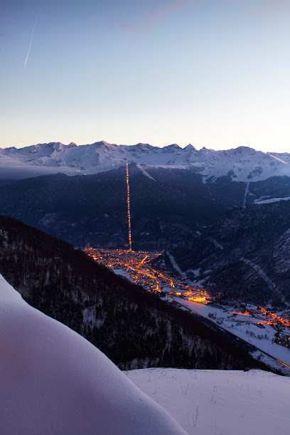 A picturesque winter scene at La Berra ski resort in Switzerland, featuring skiers enjoying the slopes, ski lifts in motion, a charming challet, and the snow-capped mountain backdrop.