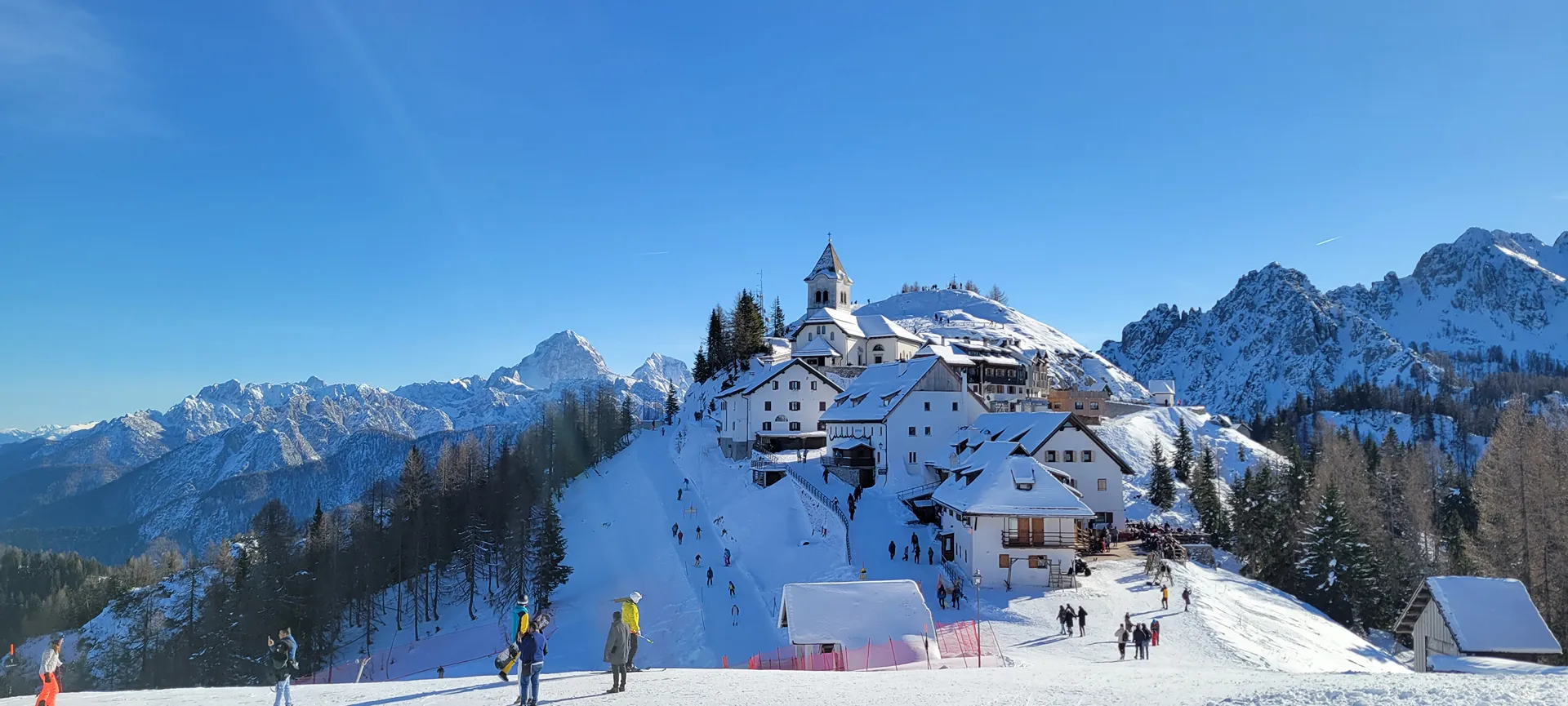 Tarvisio – Monte Lussari in Italy - a group of people skiing down a snow covered mountain.