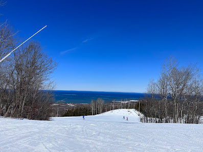 Winter sports scene at Blue Mountain Resort in Ontario, Canada, featuring a skier on snow-covered slopes, a ski lift, and overlooking views of the ski resort.