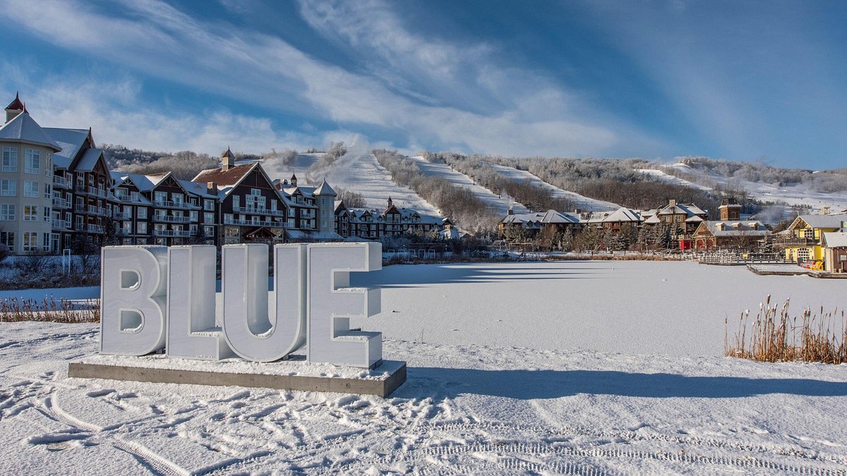 Blue Mountain Resort in Canada: a sign in the snow with buildings in the background.
