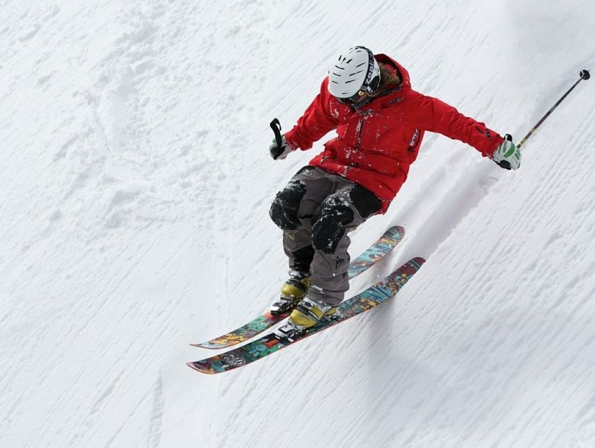 A skier is gliding through the snowy landscape of Far North Bicentennial Park in Anchorage Alaska. A snowboarder can also be seen in the backdrop with the park's winter splendor stretching out around them.