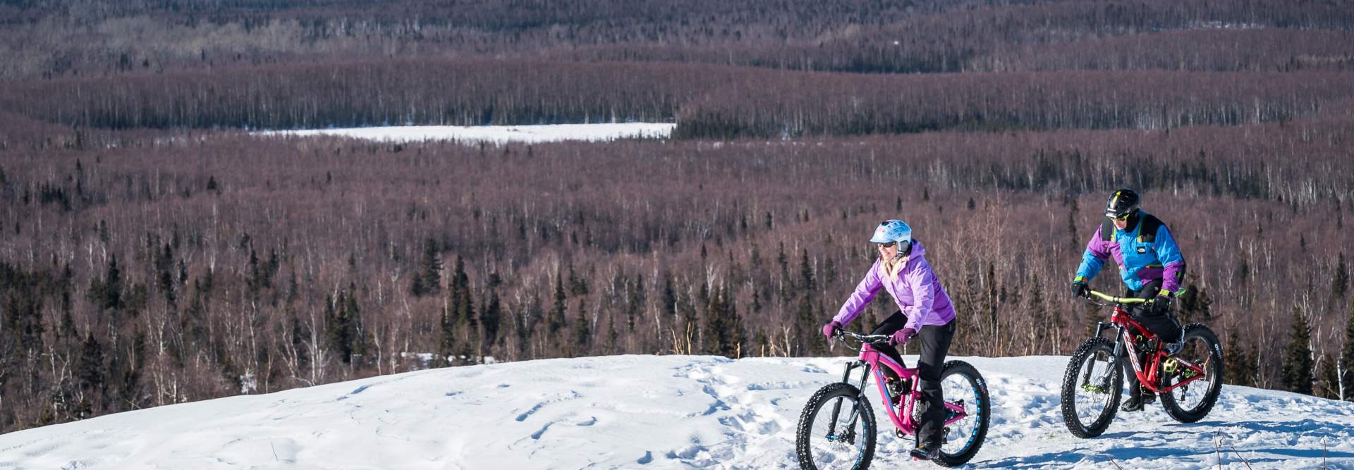 Far North Bicentennial Park in USA - two people riding bikes on a snow covered mountain.
