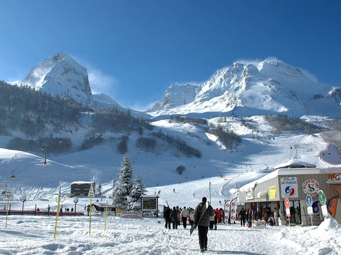 Station Gourette in France - a group of people standing on top of a snow covered mountain.
