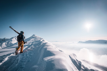 A skier and a snowboarder enjoying the well-groomed slopes at Station Gourette against a backdrop of snow-covered mountains in the Nouvelle-Aquitaine region of France.