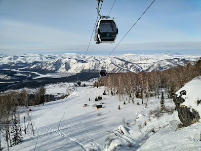 A ski lift ascends the snowy slopes of Mt. Sunapee at a crowded ski resort in Newbury New Hampshire. Skiers carve their way down the mountain enjoying the wintery scene.