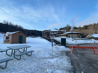 Scenic winter view of Mt Sunapee ski resort in Newbury, New Hampshire, featuring active winter sports scenes amidst snow-capped slopes and a rustic chalet.
