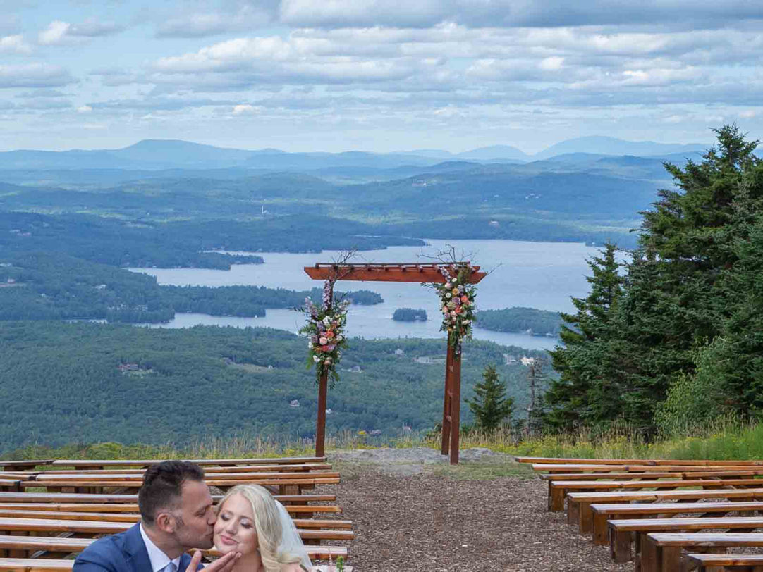 Mt Sunapee in USA - a bride and groom kissing at the top of a mountain.