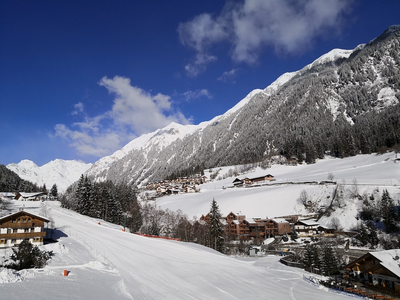 Racines-Giovo in Italy - a snow covered ski slope with houses in the background.