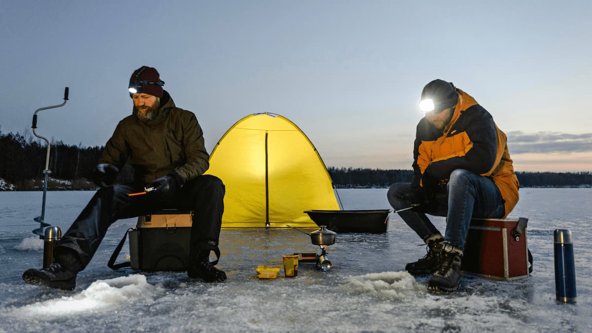Nuova Carì in Switzerland - two people sitting in the snow next to a yellow tent.