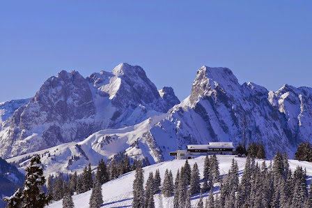 A scenic view of the popular ski resort in Innerkrems, Carinthia, Austria in winter. Vibrant snow-covered mountain peaks and busy winter sports enthusiasts create a captivating scene.