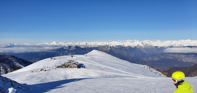 Scenic view of Montecampione Ski Area in Italy, featuring a quaint chalet, an active skier gracing the snow-covered slopes amidst a vibrant winter sports scene.