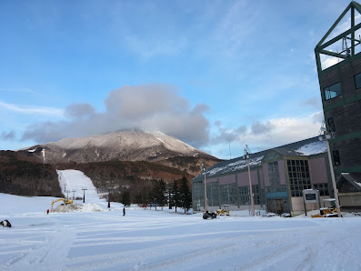 A captivating winter scene at Alts Bandai - Hoshino Resorts Nekoma Mountain in Japan, prominently featuring a bustling winter sports centre nestled amidst mountainous snow-covered terrain.