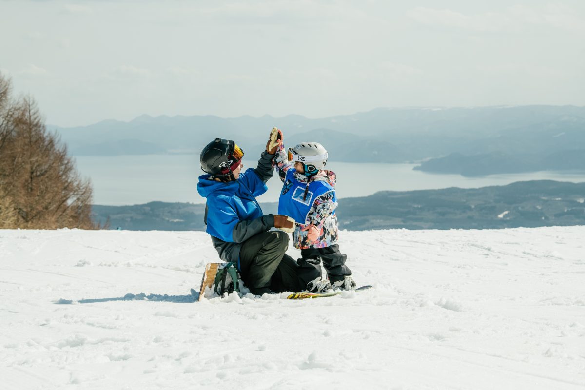 Alts Bandai - Hoshino Resorts Nekoma Mountain in Japan - two people sitting on top of a snow covered hill.