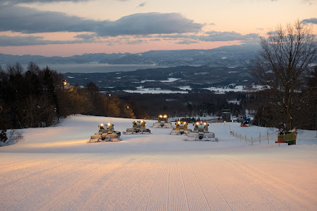 View of Alts Bandai - Hoshino Resorts Nekoma Mountain in Japan, showcasing a bustling ski resort filled with winter sport enthusiasts. The captivating winter scenery includes a ski lift ascending the mountain.