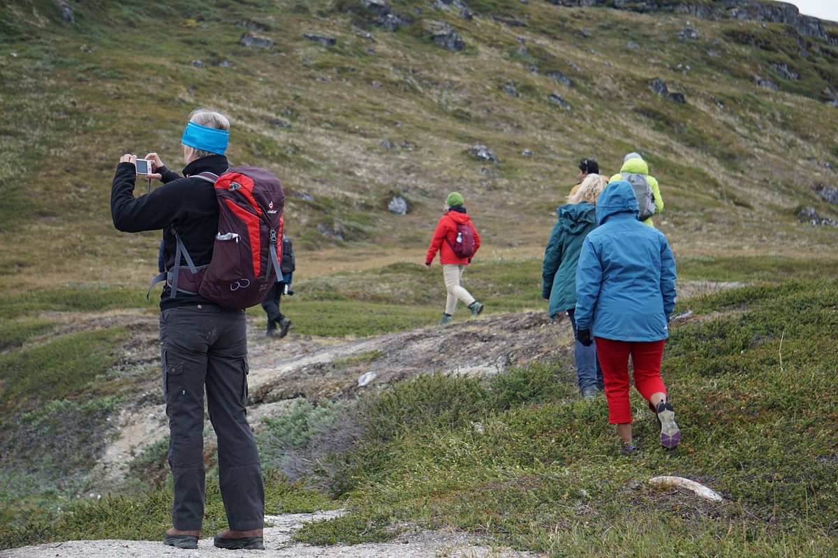 Qasigiannguit in Greenland - a group of people hiking up a mountain.