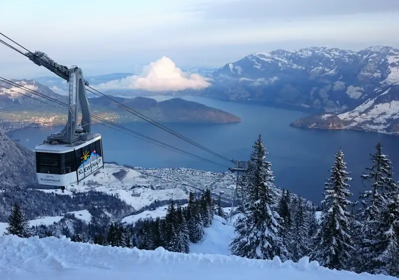 A lively winter sports scene at Klewenalp-Stockhütte in Central Switzerland featuring a skier on the slopes set against the backdrop of a picturesque ski resort with a ski lift.
