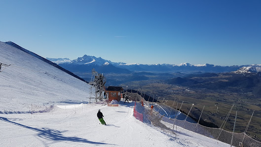 A skier gliding down the snowy slopes of Alpe du Grand Serre ski resort in France with a charming challet and majestic mountain backdrop.