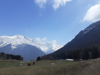 A stunning view of Alpe du Grand Serre in Grenoble, featuring a picturesque chalet nestled at the foothills of the snow-laden mountain bathed in sunlight, indicating a perfect day to explore the nearby ski resort.