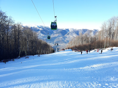 Winter scene at Straja ski resort in Romania, featuring a ski lift ascending snow-covered slopes, highlighting the thrill of winter sports amidst stunning scenery.