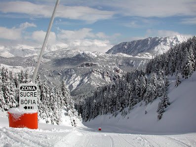 Skiers enjoying the snowy slopes of Port del Comte ski resort in Catalonia, Spain. A ski lift ascends the mountain in the background adding to the winter sports ambiance.