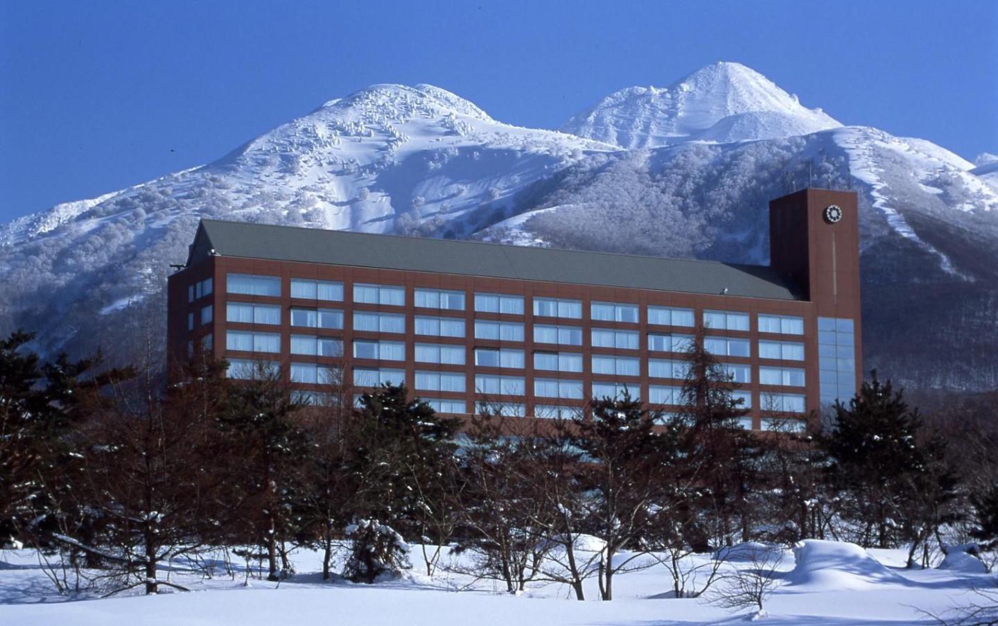 Aomori Spring in Japan: a building in the snow with mountains in the background.