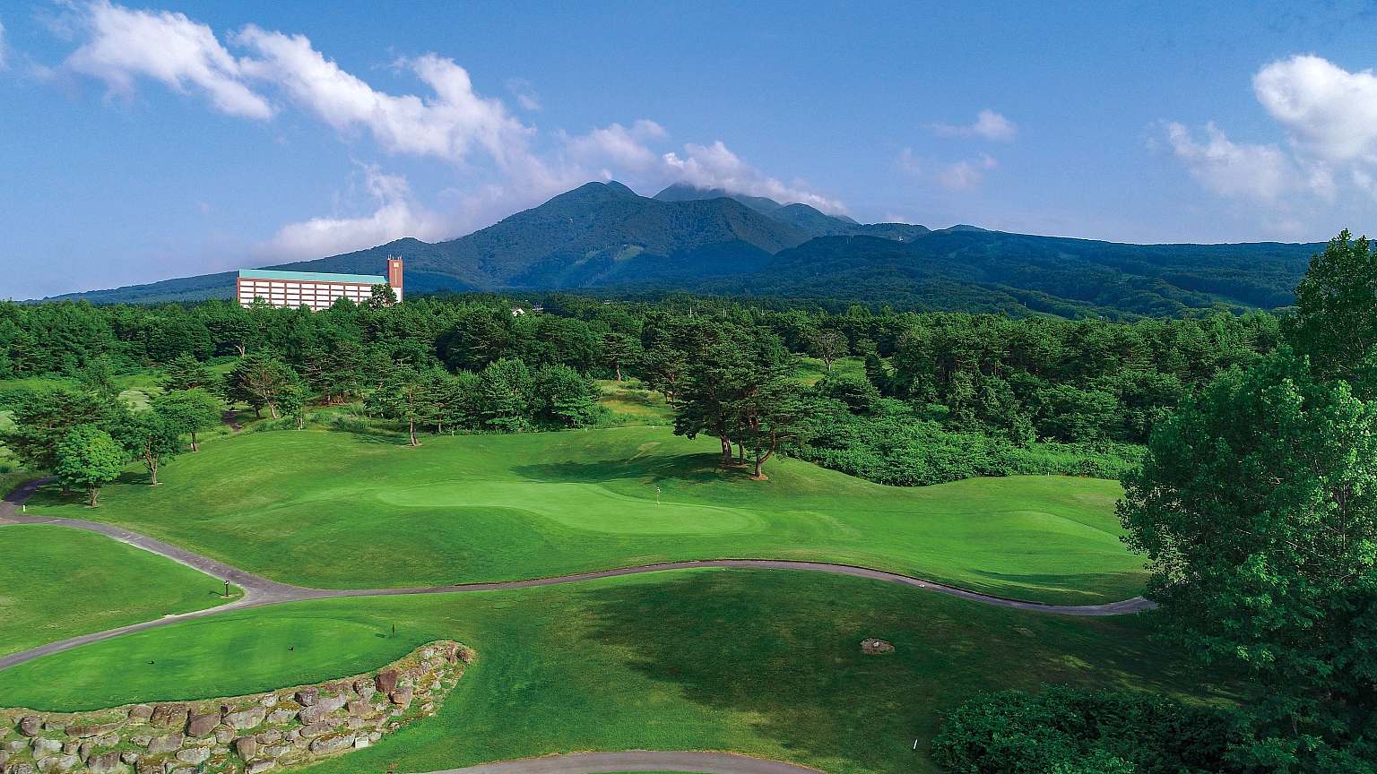 Stunning winter scene from Aomori Spring in Tōhoku, Japan, featuring a majestic snow-covered mountain, with a ski resort, a chalet, and a lodge nestled at its base.