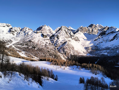 Winter scene in Valmalenco Bernina, featuring a bustling ski resort amidst stunning winter scenery with a charming chalet in view.