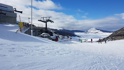 Ski resort in Deogyusan, South Korea featuring an active winter sports scene. Skiers ride up a ski lift and ski down slopes against a snowy mountain backdrop.