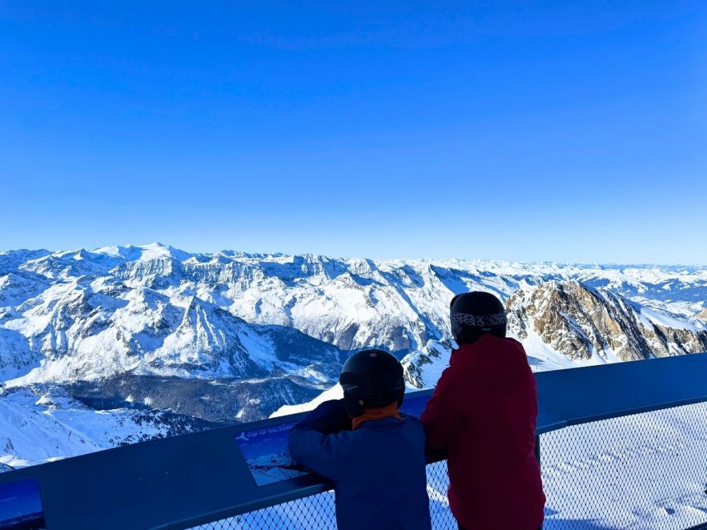 See in Austria - two people sitting on top of a snow covered mountain.