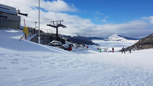 View of Campo Felice ski resort in Italy featuring winter sports scene with a ski lift and a skier. Snow-capped mountains and clear sky form a majestic backdrop.