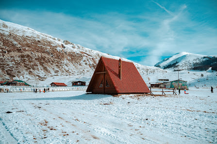 Winter sports enthusiasts enjoying lush snow-covered slopes at Campo Felice in Italy. Breathtaking winter scenery surrounds a cozy mountain hut.