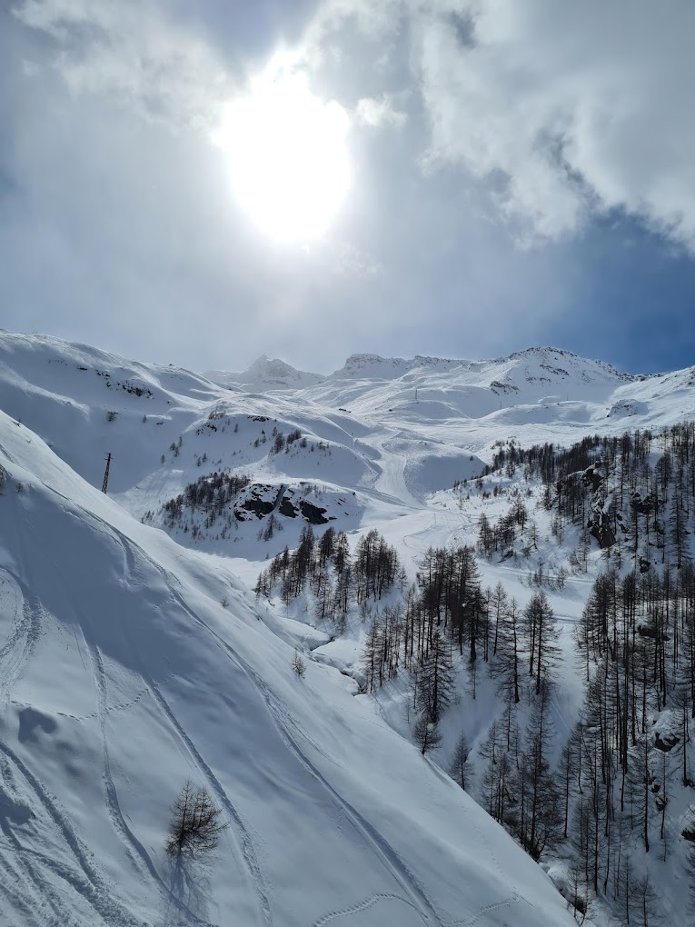 Cervinia Cielo Alto in Italy - the sun is shining over a snowy mountain.
